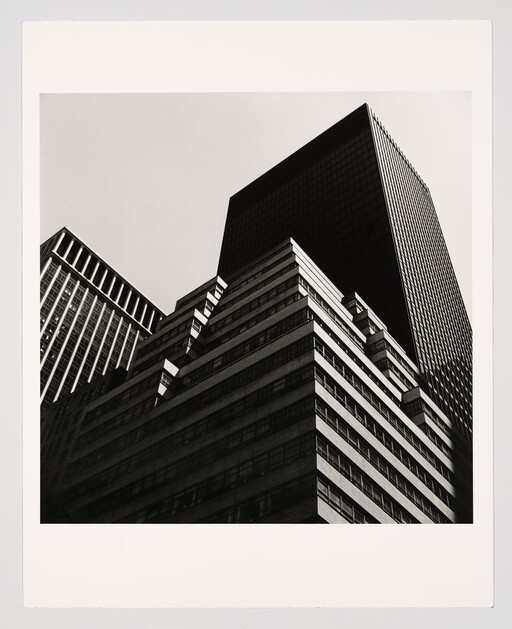 Tall black-and-white office buildings rise sharply upward against a pale sky.