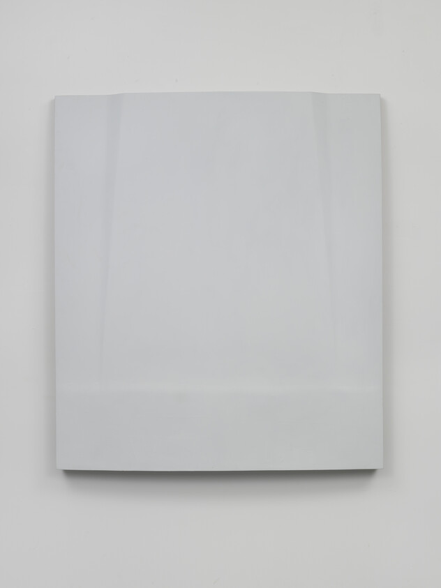 A plain white folded paper bag mounted on a white wall with soft shadows.