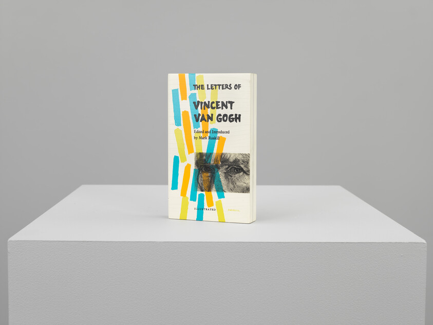A lifelike sculpture of a book titled "Van Gogh letters", feautring a image of Van Gogh's eyes and rectangular blocks of blue, yellow, and orange