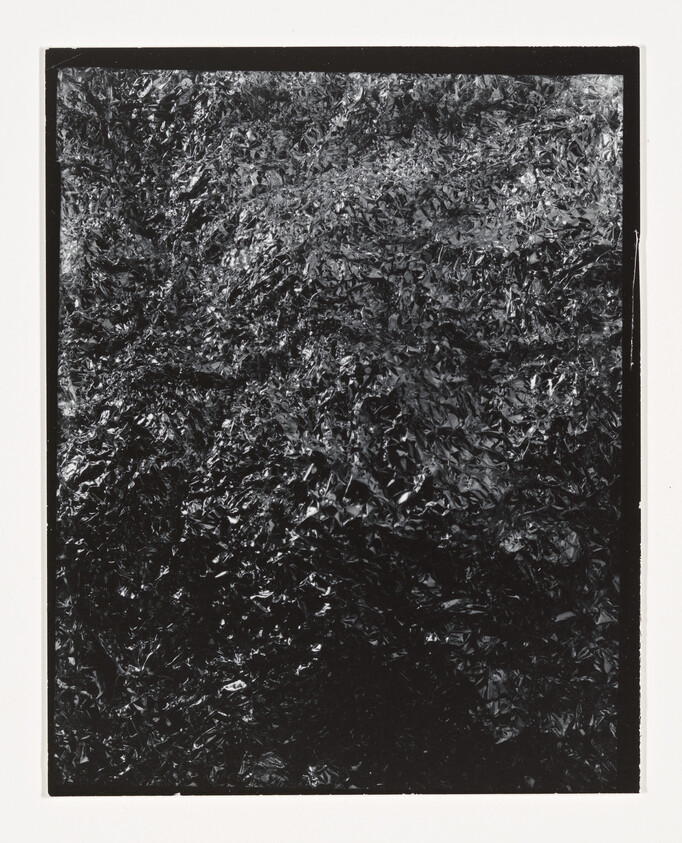 Crinkled black metallic foil with dense textured creases filling the frame.