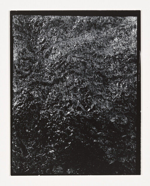 Crinkled black metallic foil with dense textured creases filling the frame.