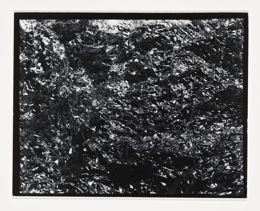 Crumpled shiny foil fills the frame with dense, reflective wrinkles and highlights.