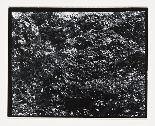 Crumpled shiny foil fills the frame with dense, reflective wrinkles and highlights.