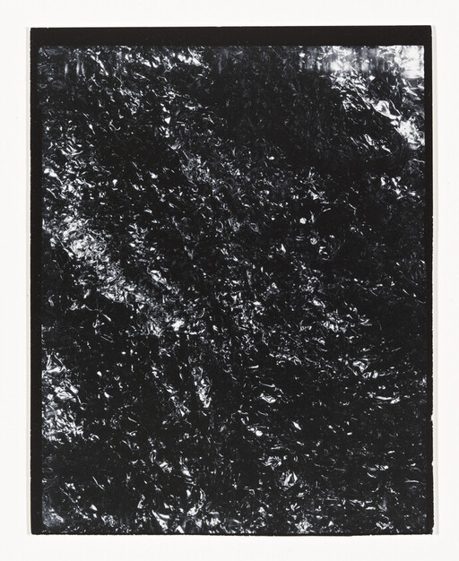A framed sheet of crinkled black foil with reflective highlights and a white border.