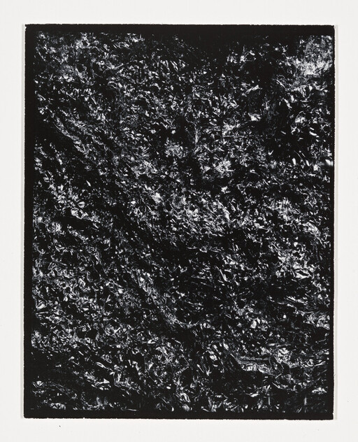 Crumpled black foil with shiny highlights inside a white rectangular border.