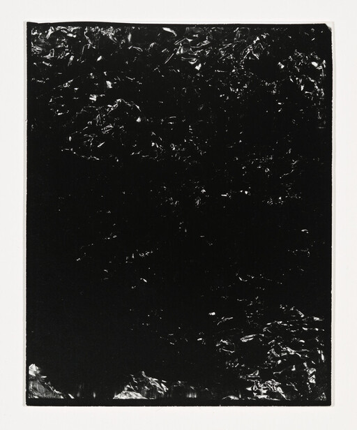 A dark rectangular sheet with a crinkled reflective surface centered on a white background.