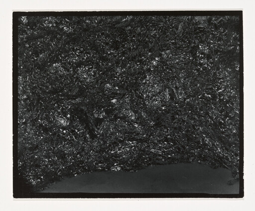 Dark crinkled shiny material fills the frame with a smooth band along the bottom.