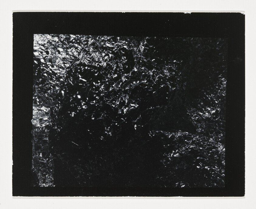 Dark crinkled metallic foil with reflective highlights framed by a thick black border.