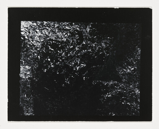 Dark crinkled metallic foil with reflective highlights framed by a thick black border.