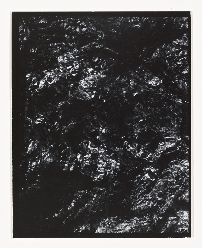 Crinkled black foil with reflective highlights framed by a narrow white border.