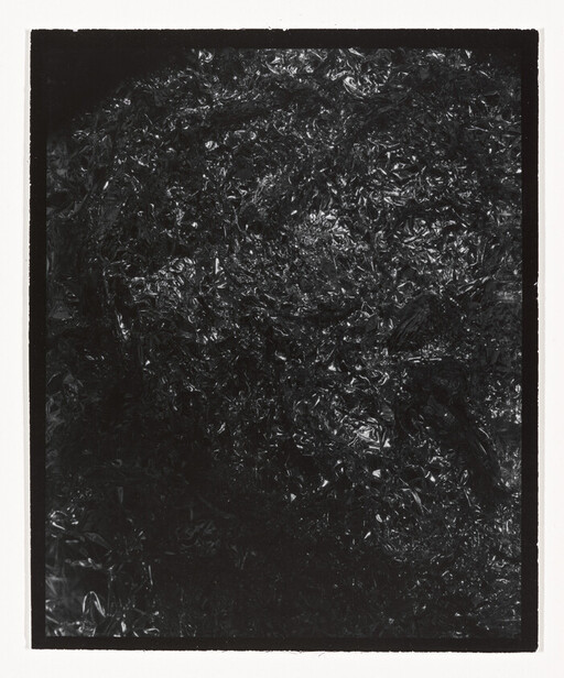 Crumpled black plastic sheet with shiny, wrinkled texture filling the frame.