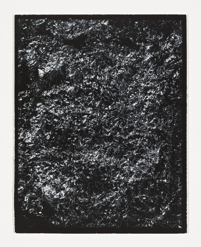 Crinkled dark metallic foil fills a rectangular frame with high-contrast shiny and matte textures.