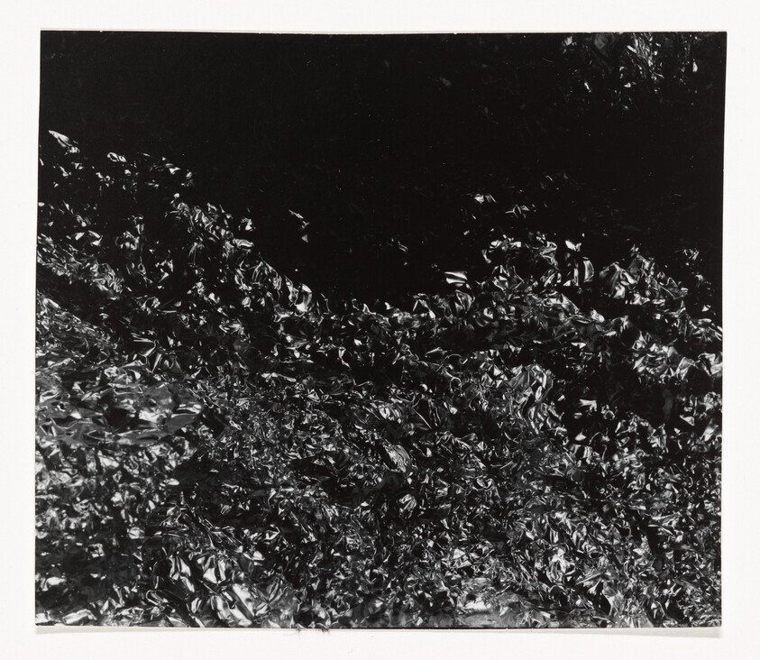 Crumpled shiny black foil fills the frame with dense, wrinkled textures and reflective highlights.