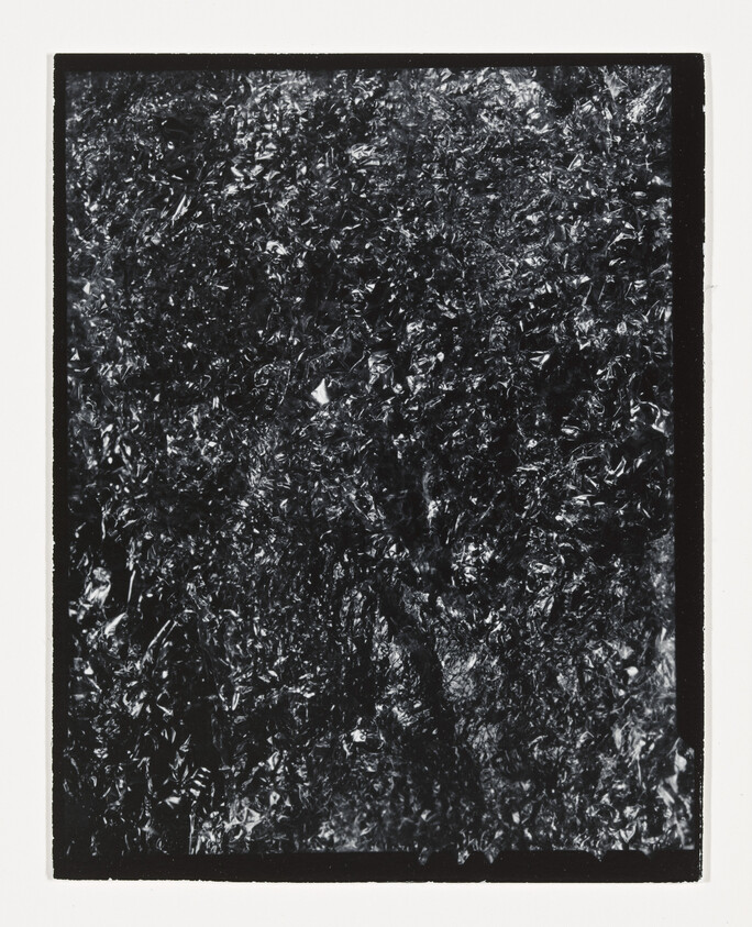 Close-up of crinkled black foil texture framed by a white border.