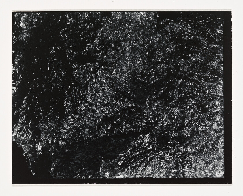 Crumpled reflective black foil filling the frame with rough, shiny wrinkles.