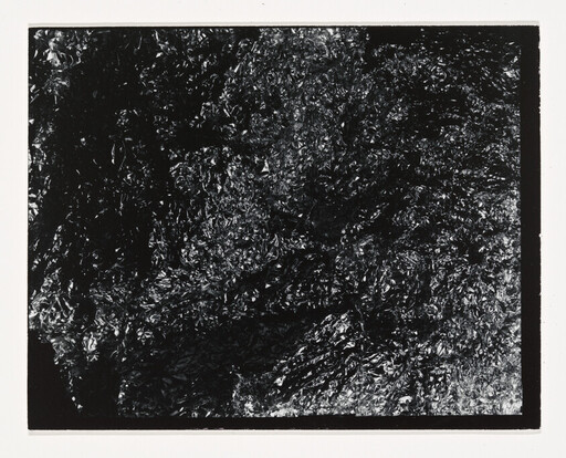 Crumpled reflective black foil filling the frame with rough, shiny wrinkles.
