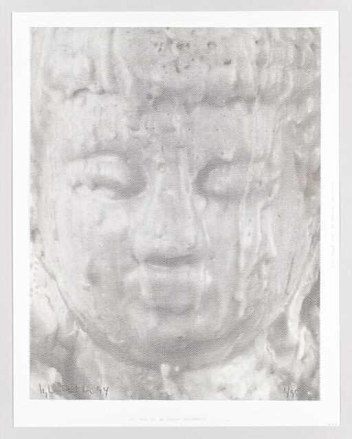 Large faded stone Buddha face with closed eyes and serene expression filling the frame.