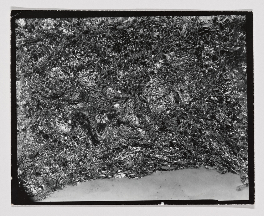 Crinkled metallic foil densely covering the upper surface with a smooth lighter strip along the bottom.