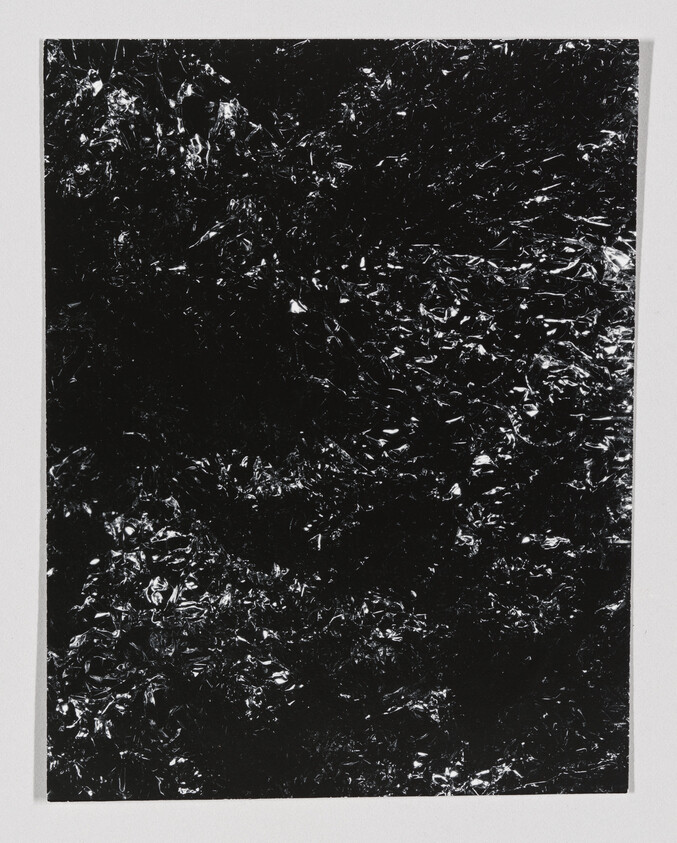 Crumpled black foil sheet with shiny highlights centered on a white background.