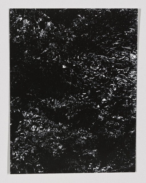 Crumpled black foil sheet with shiny highlights centered on a white background.