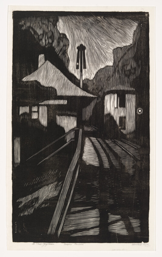 Railroad tracks lead toward houses and a tall signal post under a cloudy night sky.