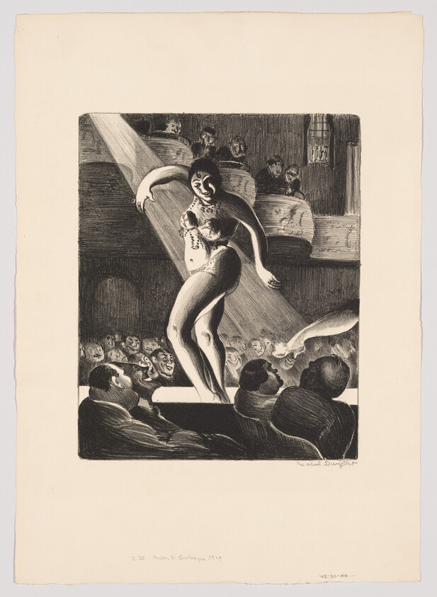 A burlesque dancer performs on stage under a spotlight while an audience watches eagerly.