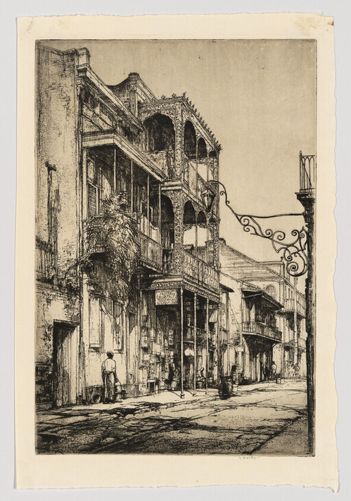 Narrow street lined with old buildings featuring ornate ironwork balconies and a few pedestrians.