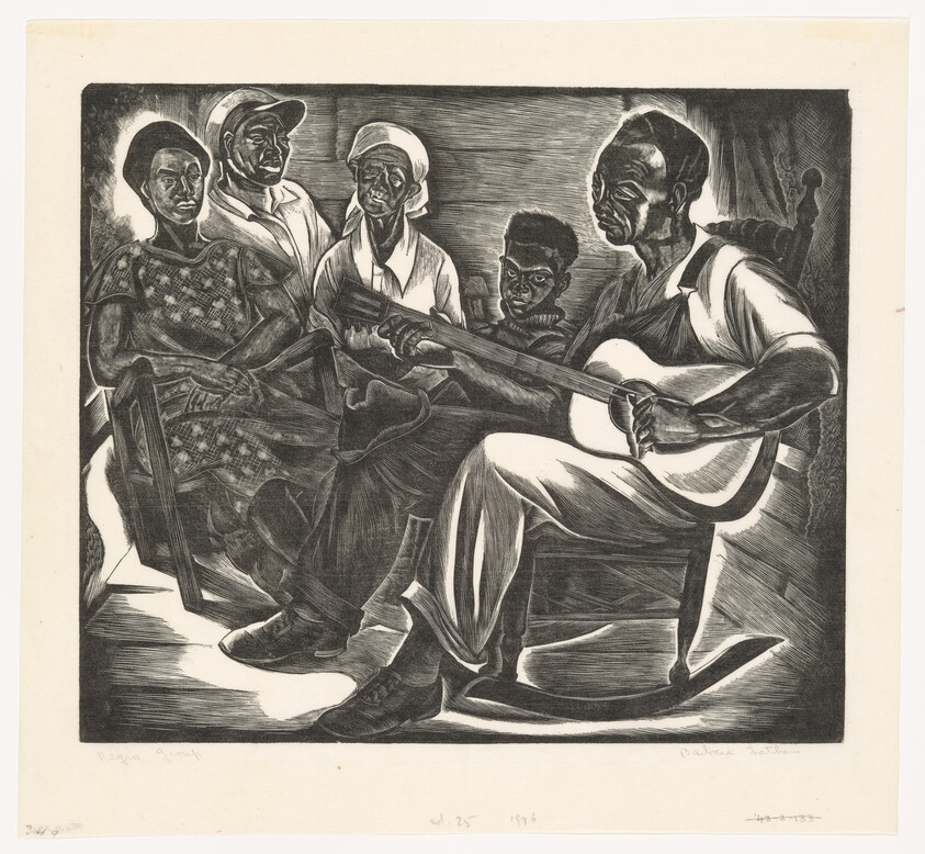 Man plays guitar while four family members sit nearby listening attentively.