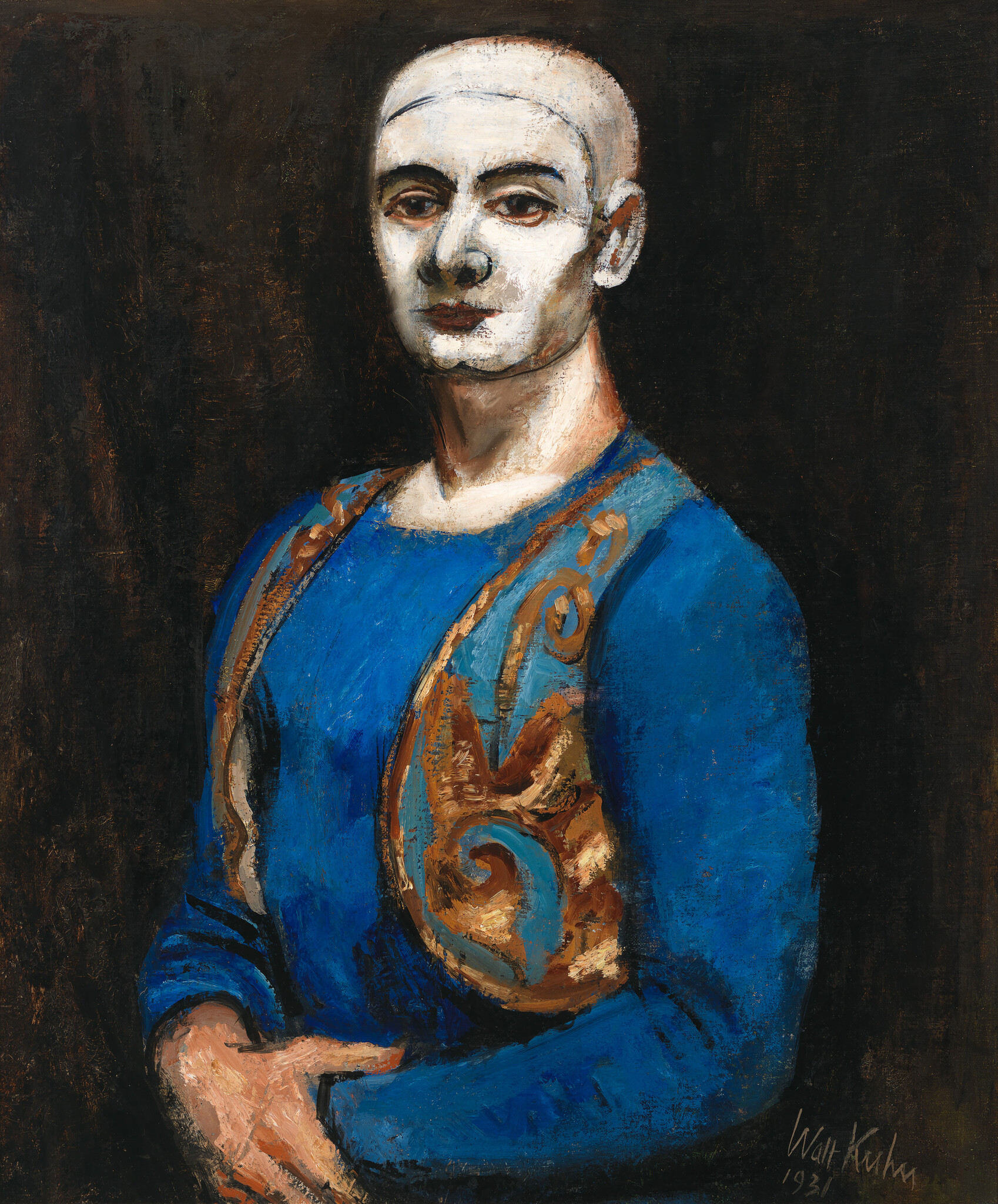 A pale-faced figure in white makeup wears a blue costume with a gold patterned vest and folded hands.