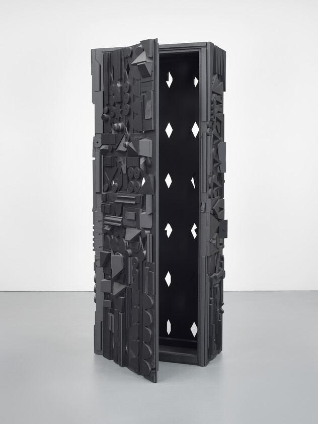 Tall, rectangular sculpture with various geometric shapes and patterns in a dark gray color.