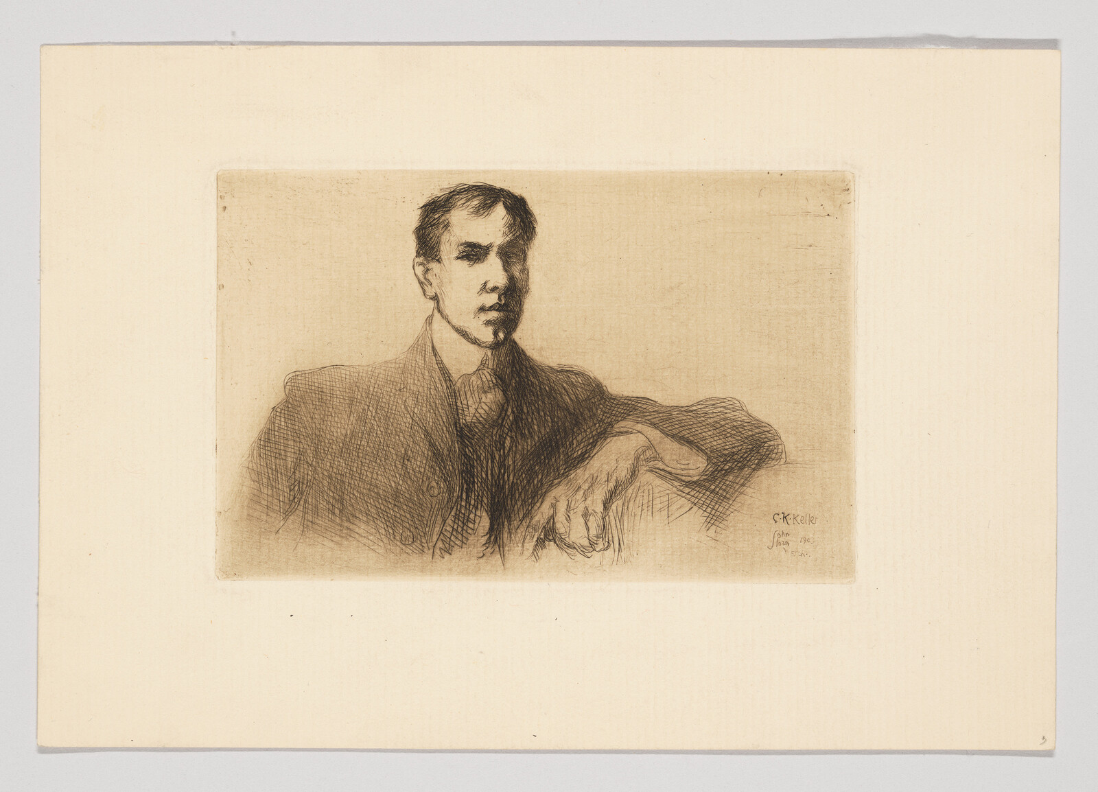 A seated man in a suit rests his arm on a surface while gazing forward.