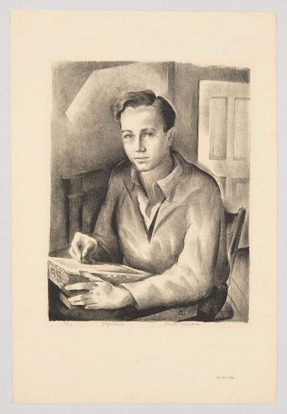 A young man sits at a table sketching in a notebook while looking toward the viewer.
