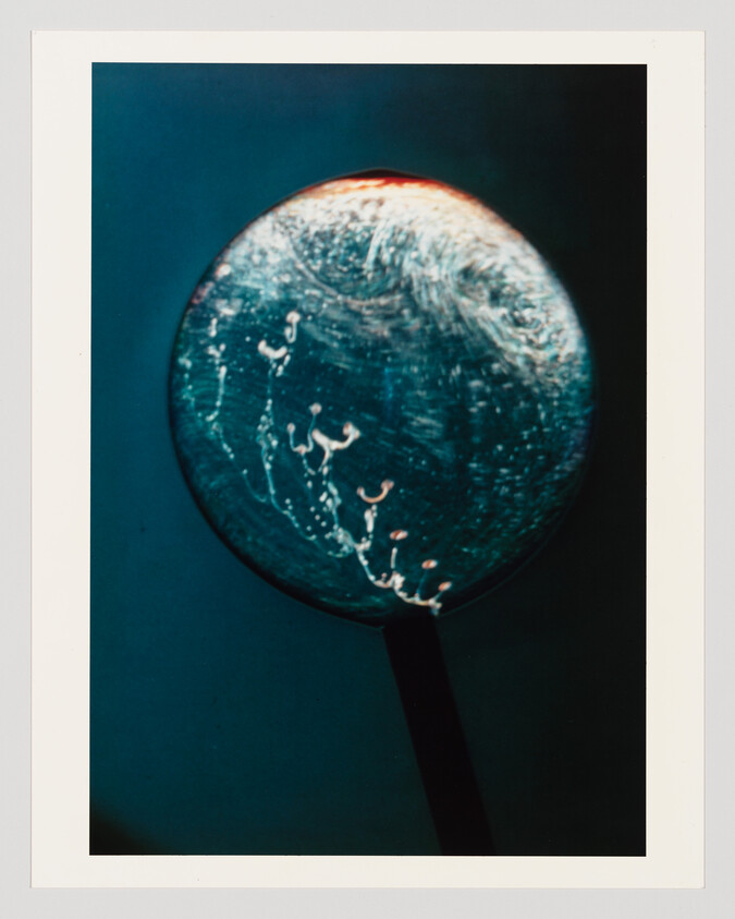 A glass sphere on a dark handle showing swirling bubbles and light reflections.