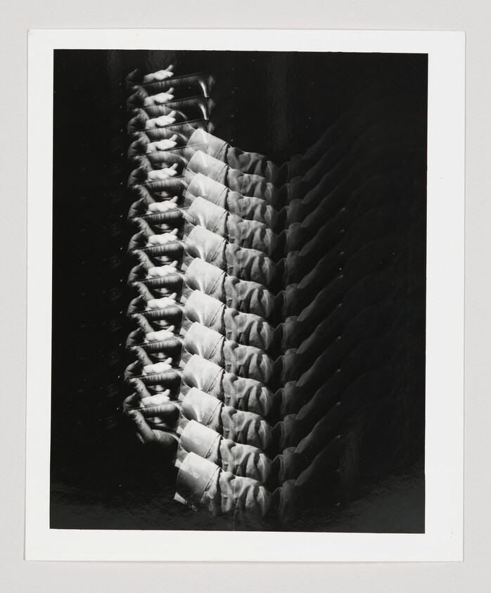 Multiple overlapping black-and-white exposures showing a row of hands clasped across a chest.