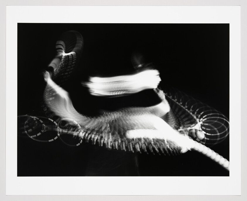 Blurred light and motion trails form abstract shapes against a black background.