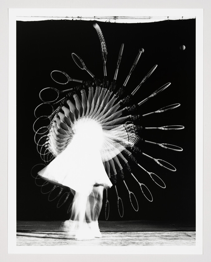 A dancer spins rapidly, creating a circular trail of repeated racket shapes.