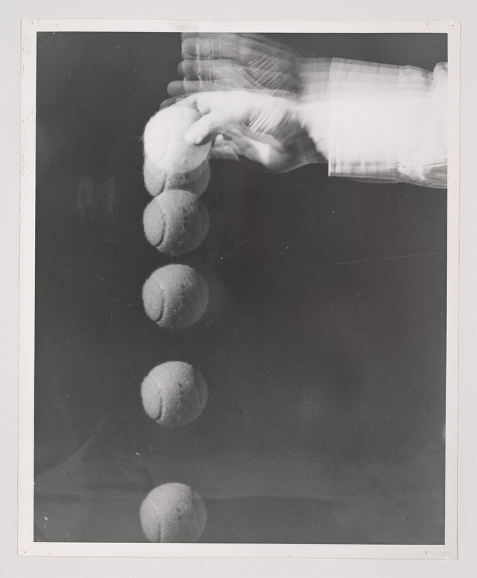 A hand releasing a tennis ball captured in multiple positions as it falls.