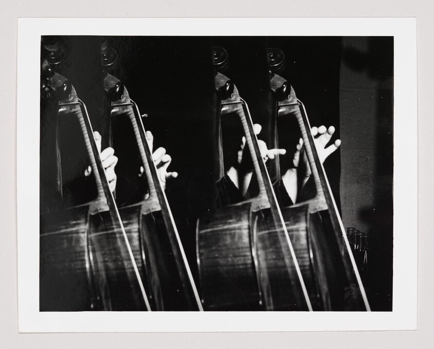 Hands moving across a double bass string create repeated overlapping images in black-and-white.