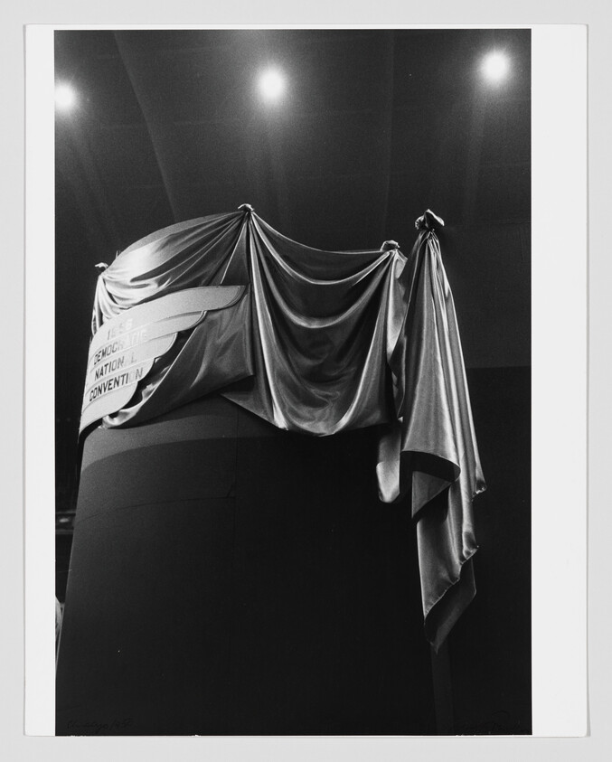 A large silky cloth drapes over a circular platform under bright overhead lights.