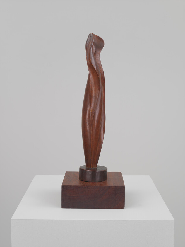 Slender, twisting wooden abstract sculpture mounted on a square wooden base on a pedestal.