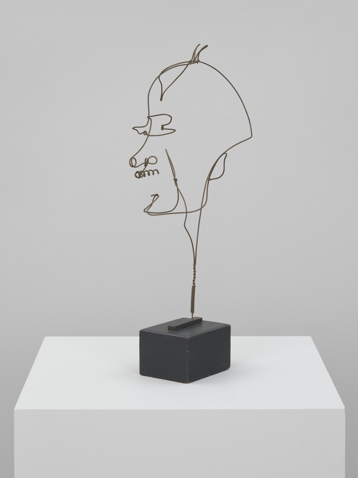 A minimalist wire sculpture depicting a human profile, mounted on a small black rectangular base.