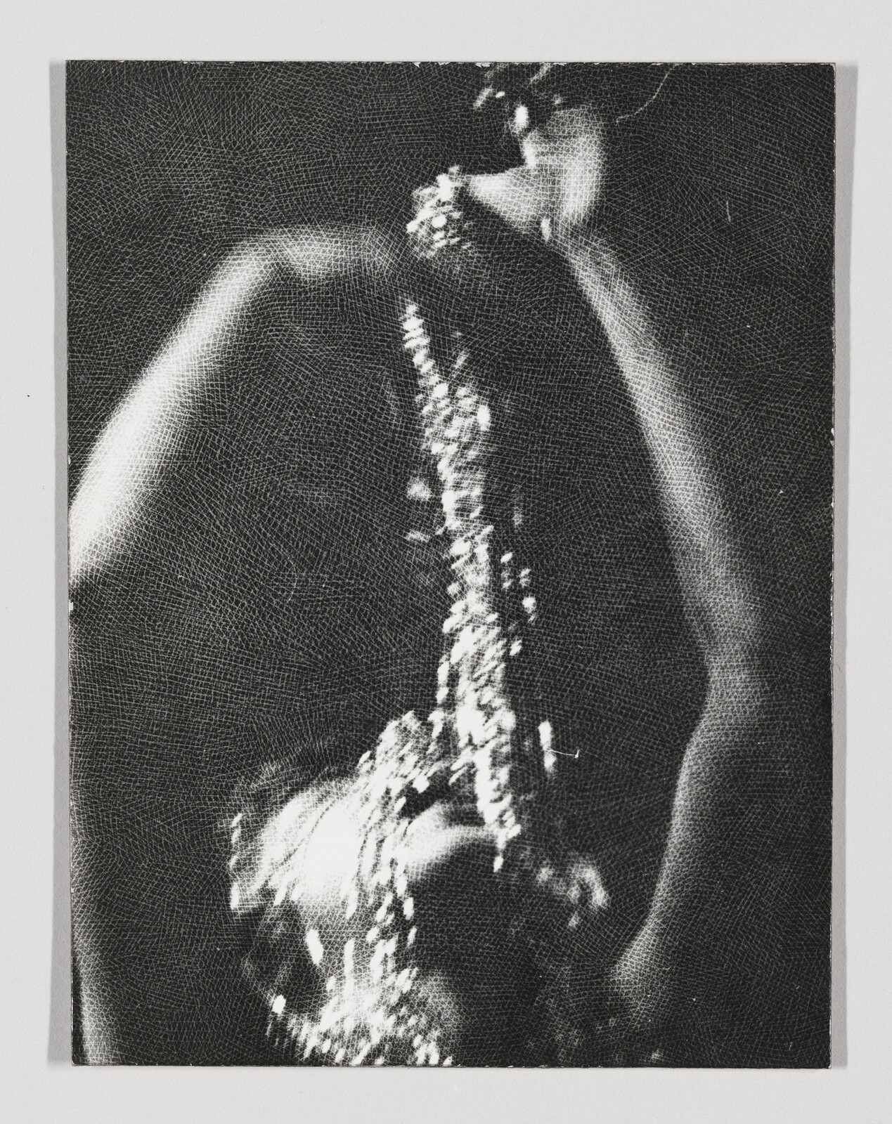 A person pours a stream of liquid over their head, creating a shimmering effect in low light.