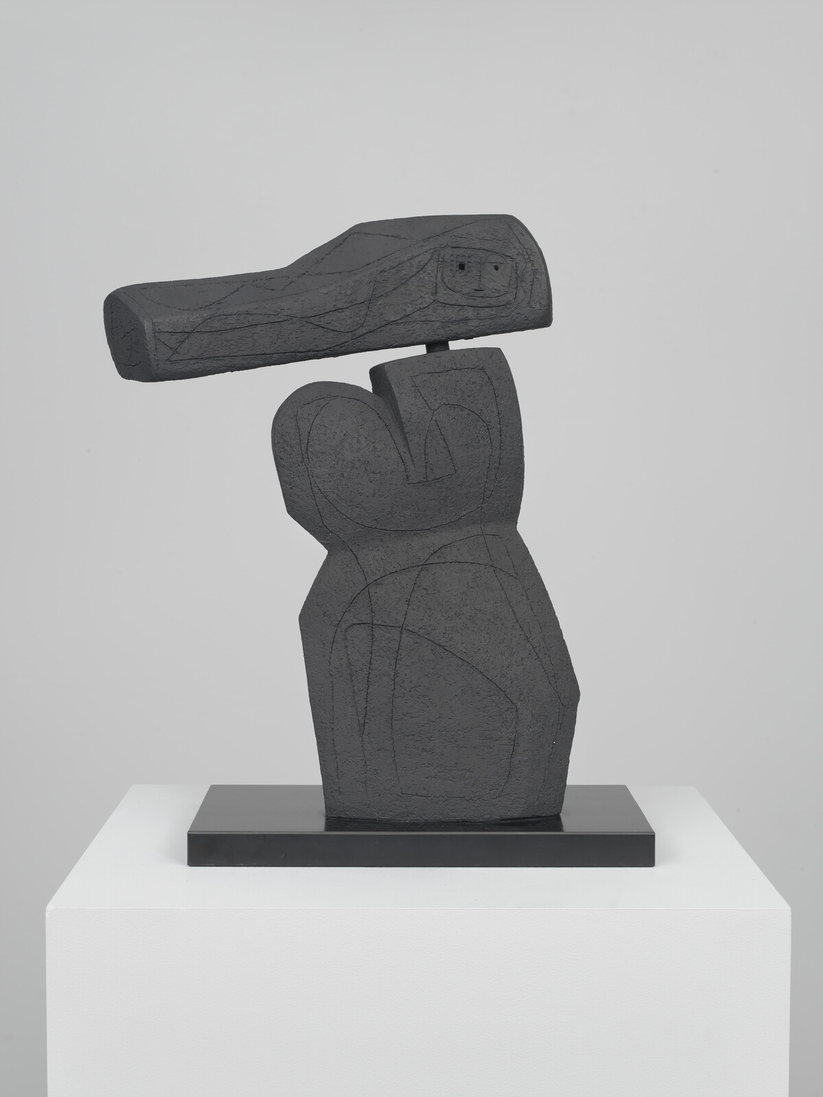 Abstract dark stone sculpture of two stacked forms with a small horizontal block balanced on top.