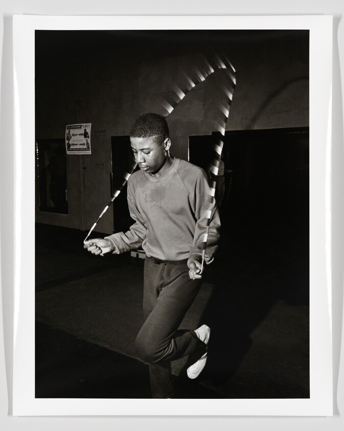Young man jump-roping with a striped rope, focused and mid-jump.