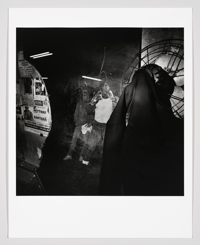 A dark shop window shows a coat hanging and a ghostly reflection of a person inside.
