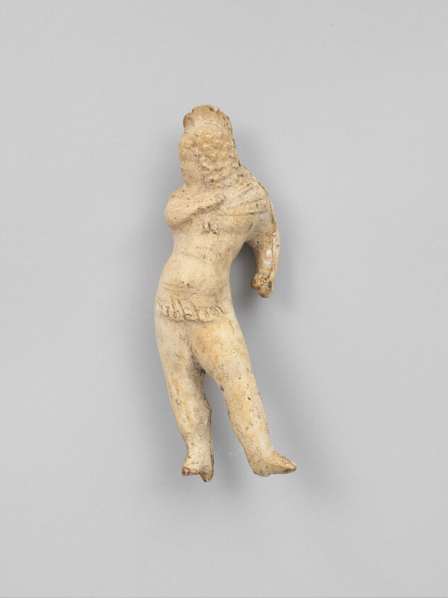 Worn terracotta figurine of a standing woman with one arm raised and simple carved details.