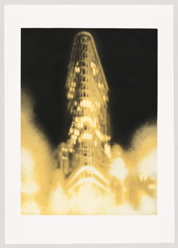 A tall, narrow skyscraper glowing with blurred golden lights against a dark sky.