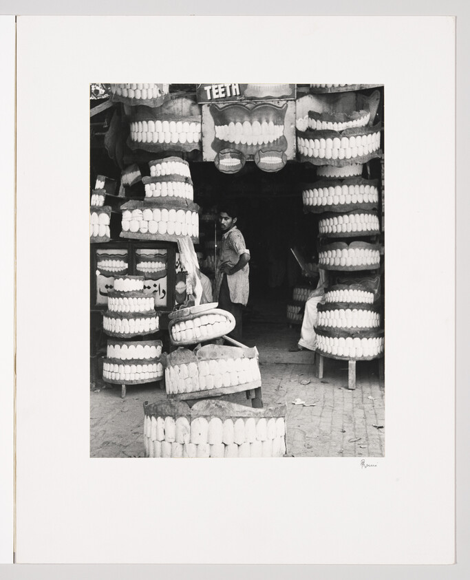 Man standing in a shop surrounded by large model teeth displays.