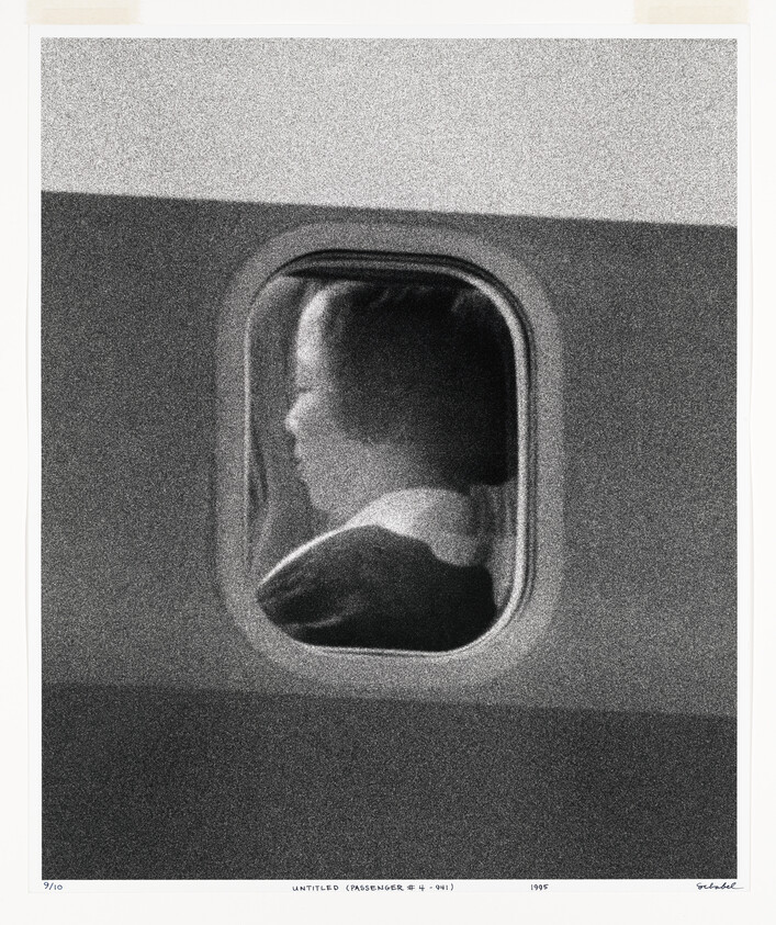 A passenger sitting in profile looking out an airplane window.