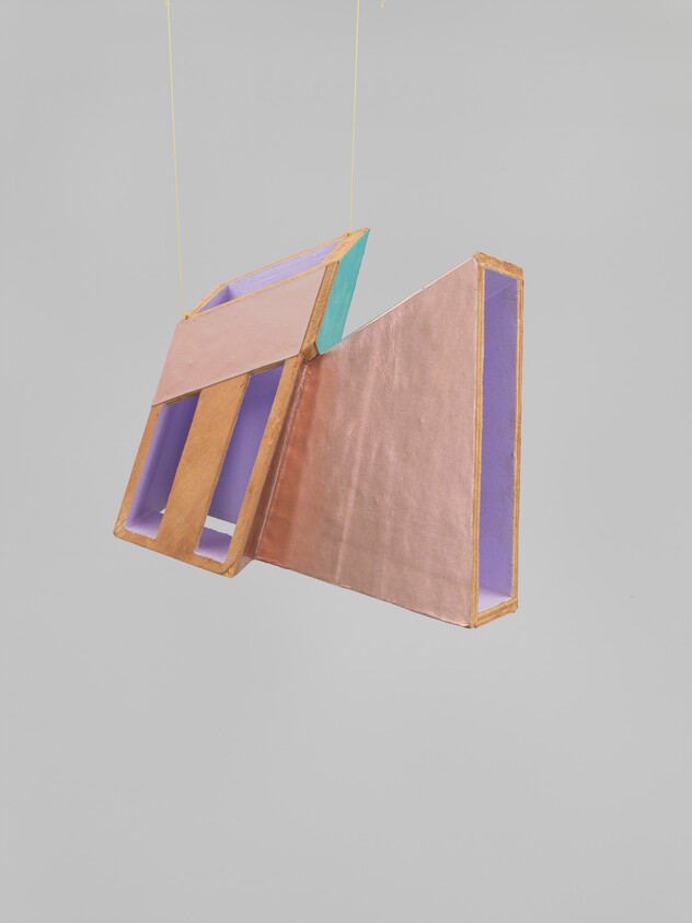 Suspended geometric sculpture with copper-colored panels and purple interior sections hanging by thin strings.